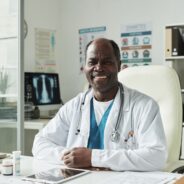 Portrait of middle aged Black man doctor sitting at desk in medical office smiling at camera with diabetes informational posters in background SSUCv3H4sIAAAAAAAACnxVyY7bOBC9D5B/MHgOMdyXHHOY2wC5BzlwU5uILBqilCAI+t9Tki011XH3xRBfba+KfOXfH/45nZB3NQf06fR7OcE59/1cp9FNuQwAk493fExDTGOL/Bi5Ii3gcntKMU9lzK5vQe+mcB7cJQE4zH2/wM+rEdXJTXNNteFyLUOUcOZ7hVh8qlMJ31u0nudpSuNfOGV87A7hvbv8AoBuQDemdM1LEG2YBDelJ6B+4LLN6evtfNoMqxEiwIS+pHLtE7pnv3Gb/WL5Pw1oQ29V3kjxObl5+vXvf66elwt4lCrXkPreDanM9SXp7ePb3upTGsLS617j9Zj2RsCkD4UY29Nu+V7Pvg2mxHDxKCKOyV3qlNfbbiMsO9QTD6N9flqrXc9lKq8SHMI/zzUPqdaHpO83fqieGGXCacwsDVgYwrAN1GNBQuetMsLZeCigPLOSRwgwhoGbtNgTbnFk2kbDKeU+vhS/fTw372lMfXK3l33ngbTw0rnAsaVaY6G0wYYKjy2JIYikAzU7B0QANEJyzASF+l4RbADDSkdJuHNa8H2giMSOCQI8O+4kFtxR7BUnuHMysi4pRYjYnaXlVikvMHExYWGDwZabDidiOQleKd2F3dlycIquw0TGDouuC9hTIjGD4XEZHVNWr2O4zR99/wmv7bJq6D4IN8dcGk39KMH1iwNvpuXy1Y3uEHcdc8jDU4OU6bwuoy1TKPMwjctN728D9aVcnQc9fjp1UCZt+NnVCu5xw1vlw+orl6bOUKb13u5ZUYTVsBwp51YKyzj8EAYXIFG7xc4Z8qx0NoLztS/L+A6K3PYb1ZJYKixlb8htdVAcPD6+Jeebi1HMvrhsCxBslMCbsG3+bRcuNqoo23b0cS2uVm04uz/rfefO/pKh/jsNSUGFebchIKveb0gL0MYbDVGmpflbbWt8jo/+RxBo1WpC7YsCDqwQlZJrriwhu8MrVogpoaiBfWB3l40VvFNYQxdXwZ9JAkpjSq2KuFPLy7RQ0kyRCHrTUlssNMjUey9xRzlUZyD0blmIz38AAAD//wMAYxjWQqAHAAA=